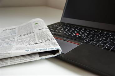 newspaper next to laptop