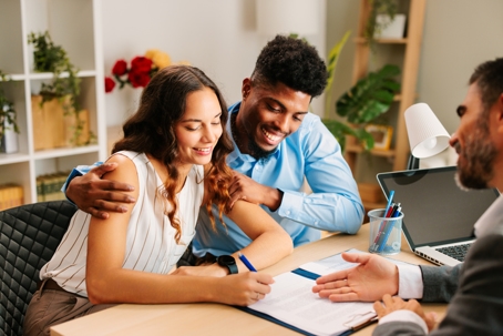 young couple signing documents at lawyer's office