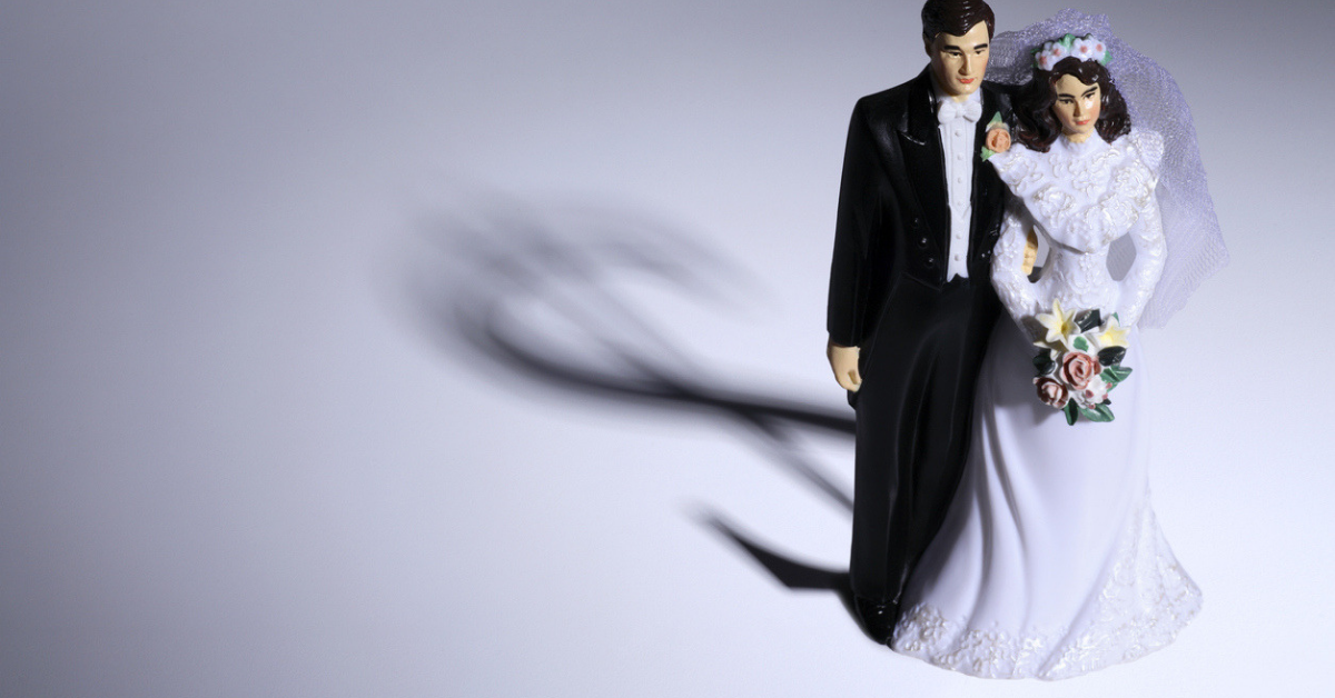 bride and groom cake topper with a dollar sign shadow symbolizing a marital agreement