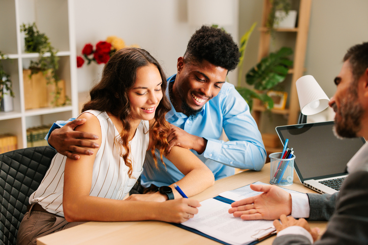 young couple signing documents at lawyer's office